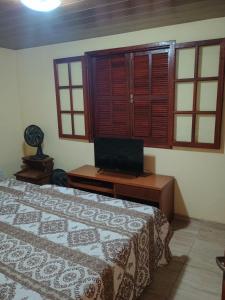 a bedroom with a bed and a tv on a table at Hospedagem do Rio in Nova Friburgo