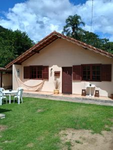a small white house with a table and chairs at Hospedagem do Rio in Nova Friburgo