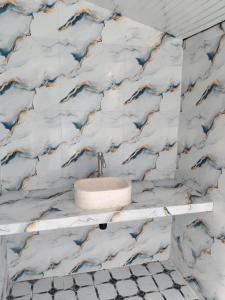 a bathroom with blue and white marble wallpaper at Djambu Tree Homestay in Biha