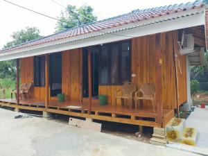 a wooden house with chairs sitting on the porch at Djambu Tree Homestay in Biha