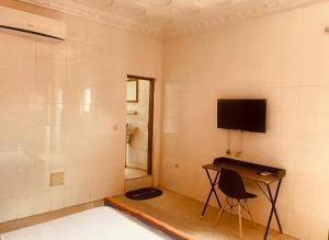 ein Zimmer mit Fernseher und Schreibtisch mit Stuhl in der Unterkunft Bethany Hotel in Abidjan