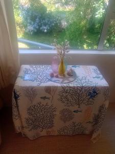a table in front of a window with a vase on it at Beside the lagoon - Waikanae Beach in Waikanae