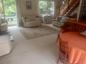 a living room with a couch and chairs and a table at Beside the lagoon - Waikanae Beach in Waikanae