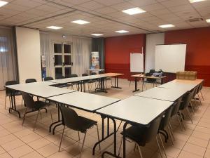 a classroom with tables and chairs in a room at Brit Hotel Lyon Nord Dardilly in Dardilly