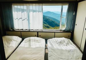 a room with two beds in front of a window at Ajisai Coral Princess Villa in Shirahama