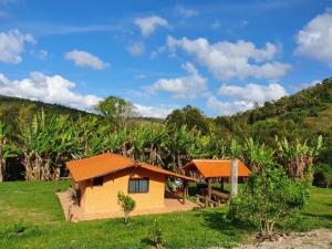 a small house with an orange roof in a field at Sossego Da Mata in Santo Antônio do Leite