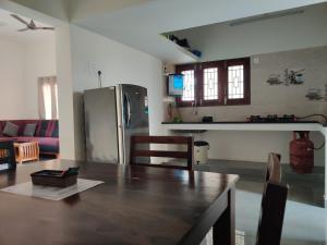 a kitchen and living room with a wooden table at Wind Chimes in Tiruvannāmalai