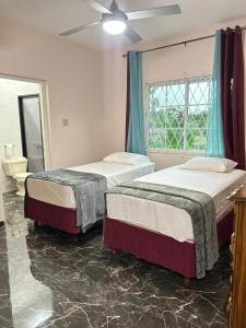 a bedroom with two beds and a window and a sink at Coke Guest House in Mandeville