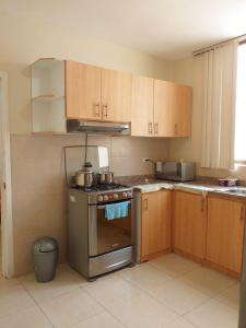 a kitchen with a stainless steel stove and wooden cabinets at Urbanization Maratea in Manta
