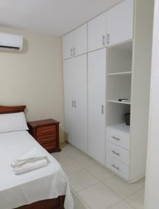 a white bedroom with a bed and white cabinets at Urbanization Maratea in Manta +14 photos
