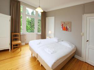 a bedroom with a large white bed and windows at Group Villa with Pool & Sauna in Wanze