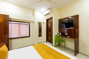 a room with a bed and a desk and a television at Imperial Hotel Near Haji Ali in Mumbai