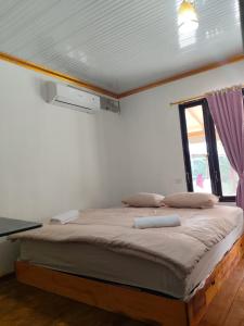a bedroom with a bed in a room with a window at Djambu Tree Homestay in Biha