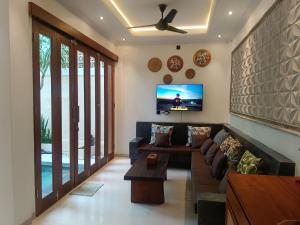 a living room with a couch and a tv at Artha Sadia Villa 2 Seseh Beach in Cemagi