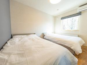 two white beds in a room with a window at torinuma VILLA in Furano