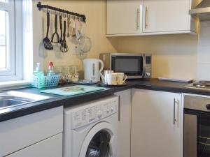 a kitchen with a washing machine and a microwave at Ashley Cottage in Bowmore