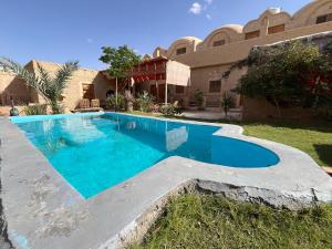 a swimming pool in front of a house at Agpeninshal Ecolodge in Siwa