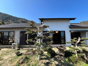 a house with a tree in front of it at Beachfront Irori in Suo Oshima