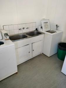a white kitchen with a sink and two microwaves at Albany Bayview Lodge in Albany +59 photos