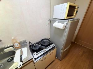 a small kitchen with a stove and a microwave at サクセスハイム 203 in Miyazaki +7 photos