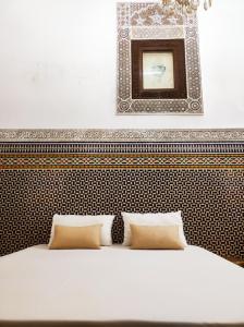 a bed with two pillows and a mirror above it at Riad Benkirane Fes Medina in Fez +32 photos