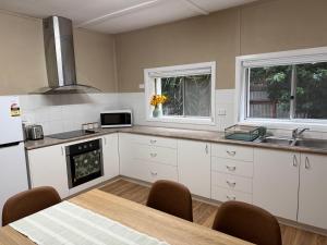 a kitchen with white cabinets and a table and a microwave at Kangaroo Cottage in Hay
