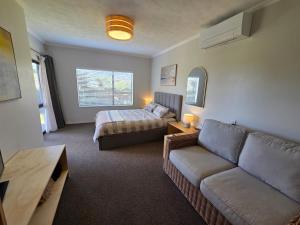 a living room with a couch and a bed at Links View Retreat in Omokoroa +4 photos