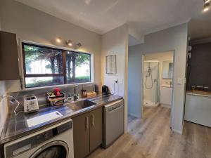 a kitchen with a sink and a washing machine at Links View Retreat in Omokoroa