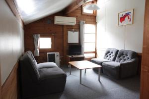 ein Wohnzimmer mit zwei Sofas und einem Fernseher in der Unterkunft miscu in Minakami