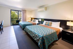 a hotel room with two beds and a balcony at Royal Motel Miles in Miles