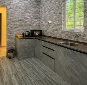 a kitchen with a sink and a brick wall at Irida 2bhk private pool viila in Assagao