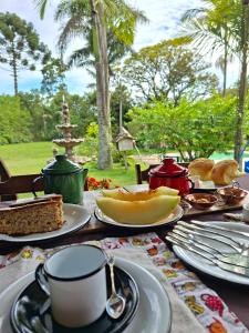 a table with plates of food and a cup of coffee at Chalé Rústico Rota Bar 448 in Correia de Almeida