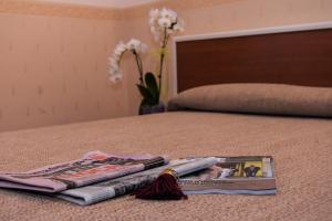 een stapel tijdschriften op een bed met een boek bij Albergo Munsci' in Rovello Porro