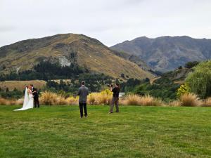 a group of people taking pictures of a bride and groom at Tucker Beach Private Exclusive Retreat in Queenstown