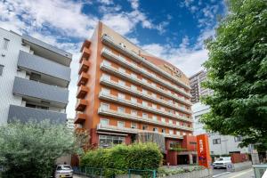 a tall orange building in a city at Hotel 1-2-3 Takasaki in Takasaki