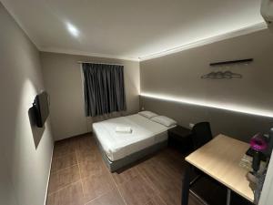 a small room with a bed and a table at Li Garden Hotel in Pasir Gudang
