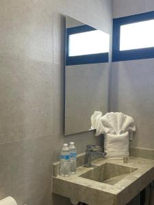 a bathroom with a sink and a mirror and towels at Hotel Posada Gabriel in Mazatlán