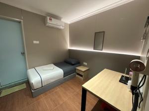 a small room with a bed and a table at Li Garden Hotel in Pasir Gudang +4 photos