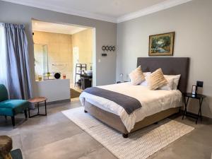 a bedroom with a large bed and a bathroom at Nest - The Homestead in Howick