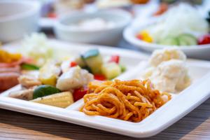 a plate of food with noodles and vegetables on a table at Hotel 1-2-3 Takasaki in Takasaki