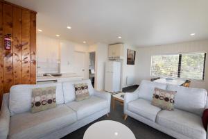 a living room with two couches and a kitchen at Hahei Island Views in Hahei