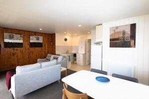 a living room with a table and a kitchen at Hahei Island Views in Hahei