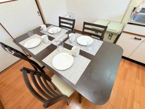 a black table with plates and cups and chairs at パームハウス 202 in Miyazaki