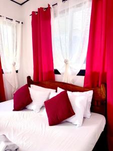 a bedroom with red curtains and a bed with white pillows at Placido's Vacation Home in Puerto Galera