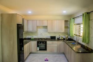 a kitchen with white cabinets and a black counter top at Casuarina Apartments in Livingstone