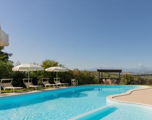 a large swimming pool with chairs and umbrellas at Agriturismo Villa Fiore in Torano Nuovo
