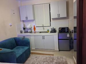 a kitchen with white cabinets and a blue couch at BoniMark in Machakos