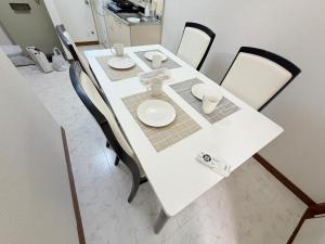 a white table with white plates and cups on it at パームハウス 203 in Miyazaki