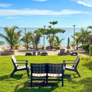 two benches sitting in the grass near the beach at Solsticio Azzul Beach Resort in Pandan