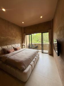 a bedroom with a large bed with a large window at The Petra Boutique Studios in Ko Tao